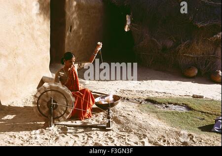 Rural woman using spinning wheel or charkha ; Bikaner ; Rajasthani ; India Stock Photo