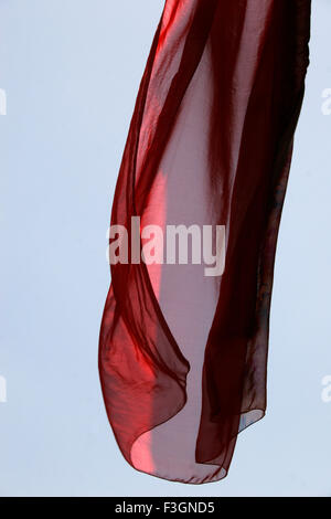 Abstract Indian traditional ladies wear saree red color flying air against blue skies wind while hanging drying Pune Stock Photo