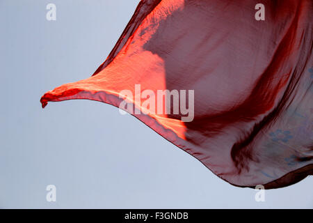 Abstract Indian traditional ladies wear saree red color flying air against blue skies wind while hanging drying wash Pune Stock Photo