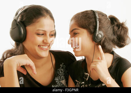 Maharashtrian and Gujarati teenage and eleven year old girls listening to music using earphone MR#686M;191 Stock Photo