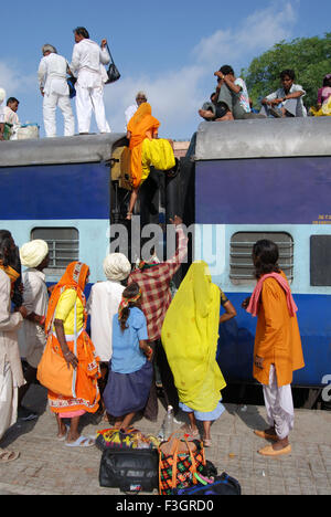 Woman climbing on roof of train on railway station ; Jodhpur ; Rajasthan ; India Stock Photo