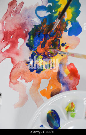 Brush mixing paint on palette-Artist's hand applying paint gouache on the drawing sheet Stock Photo