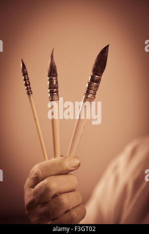 Painter's hand holding three paintbrushes Stock Photo
