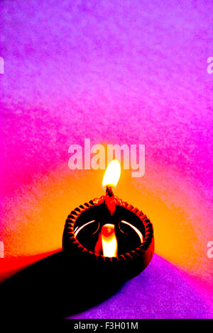 Fine art ; single one diya clay oil lamp a source of light as flame on colorful background Stock Photo