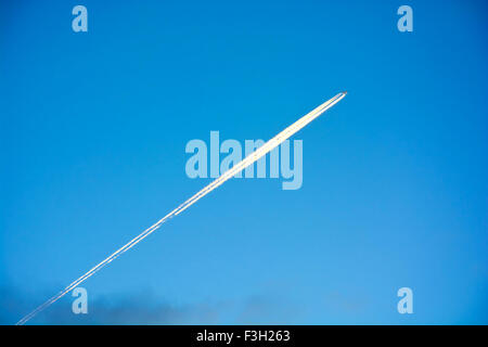Plane and plane trails on the blue clean sky. Stock Photo