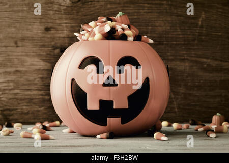 a carved pumpkin full of different halloween candies, on a rustic wooden background, with a filter effect Stock Photo