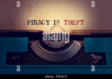 closeup of a blue retro typewriter and the text piracy is theft written with it in a yellowish foil Stock Photo
