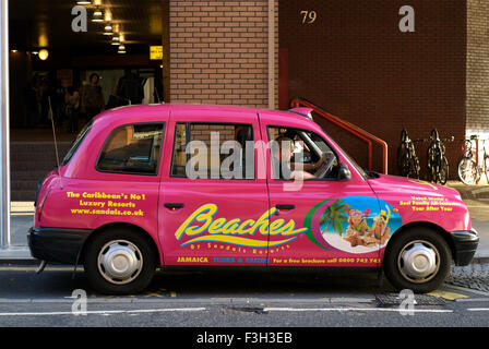 Driver reading paper in pink taxi ; Harrow On The Hill London ; U.K. United Kingdom England Stock Photo