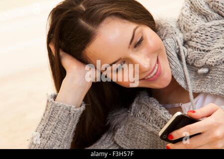 Young woman resting on elbow using smartphone smiling Stock Photo