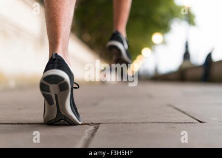 Young male runners wearing trainers running on sidewalk Stock Photo