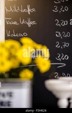 Yellow flowers in front of cafes chalkboard menu, focus on background Stock Photo