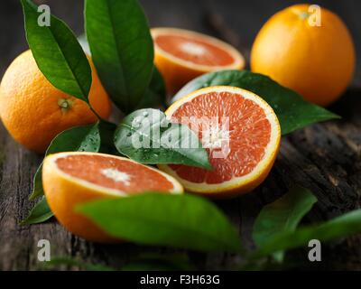 Oranges whole and halved on tree bark Stock Photo
