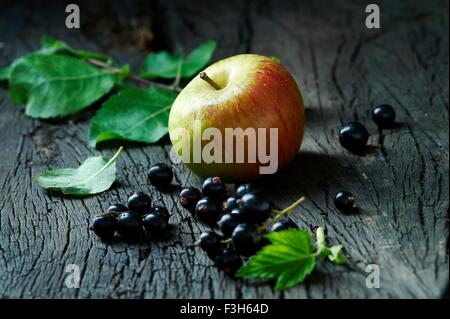 Cox's apples and blackcurrants on old wooden surface Stock Photo