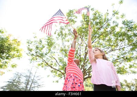 Girls holding up American flags in park Stock Photo
