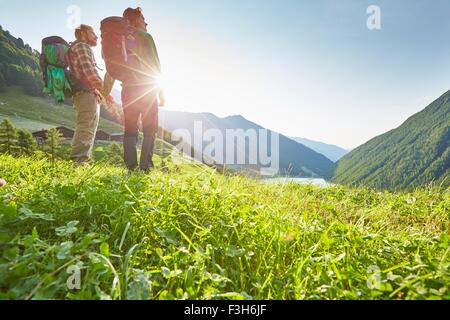 Young hiking couple looking out over Vernagt reservoir and Finailhof farmhouse, Val Senales, South Tyrol, Italy Stock Photo
