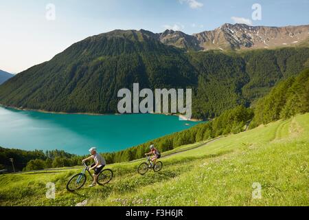 Young couple mountain biking at Vernagt reservoir, Val Senales, South Tyrol, Italy Stock Photo