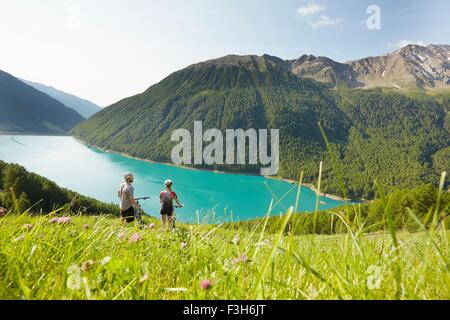 Young couple on mountain bikes looking out at Vernagt reservoir, Val Senales, South Tyrol, Italy Stock Photo