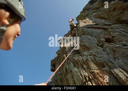 Low angle view of young rock climbing couple climbing rock formation, Val Senales, South Tyrol, Italy