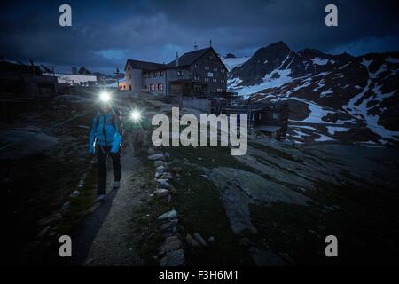 Young couple hiking at night wearing headlamps on path at Val Senales Glacier, Val Senales, South Tyrol, Italy Stock Photo
