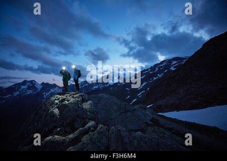 Young hiking couple looking out over rugged mountains at night, Val Senales Glacier, Val Senales, South Tyrol, Italy Stock Photo