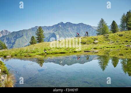 Young couple mountainbiking down hill, Karthaus, Val Senales, South Tyrol, Italy Stock Photo
