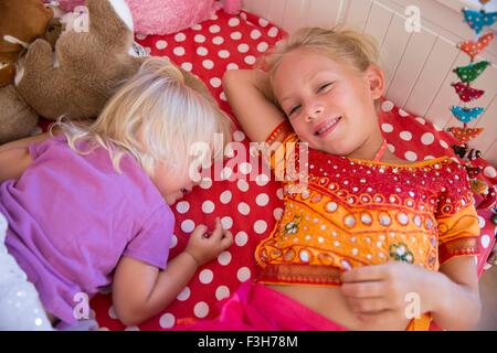 Portrait of two young sisters lying on bed Stock Photo