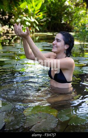 Young woman wearing bikini with hands behind head relaxing on