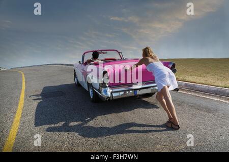 Woman pushing Convertible on road Stock Photo