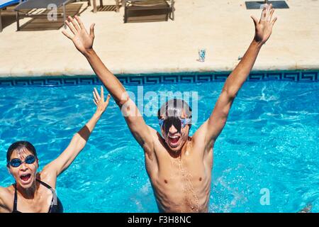 Portrait of young man and mother with hands raised in swimming pool Stock Photo