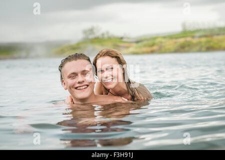 Portrait of smiling young couple relaxing in Secret Lagoon hot spring (Gamla Laugin), Fludir, Iceland Stock Photo