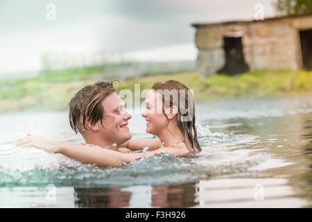 Romantic young couple splashing in Secret Lagoon hot spring (Gamla Laugin), Fludir, Iceland Stock Photo