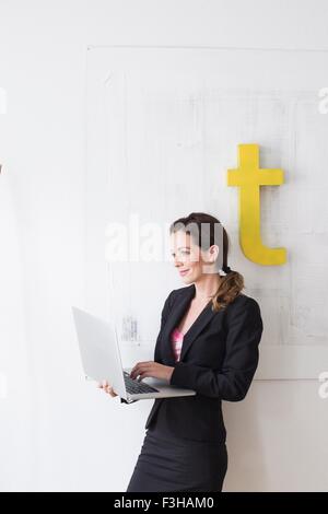 Mature woman wearing business attire standing using laptop Stock Photo