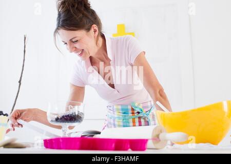 Mature woman wearing apron preparing food looking down smiling Stock Photo