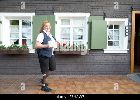 Mid adult woman with prosthetic leg, carrying mugs, outdoors Stock Photo