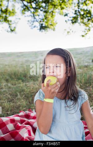 Girl eating green apple at park picnic Stock Photo