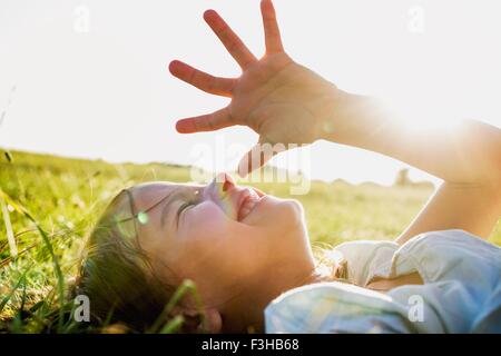Girl lying in park shielding eyes from sunlight Stock Photo