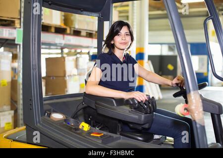 Portrait of female forklift truck driver working in distribution warehouse Stock Photo