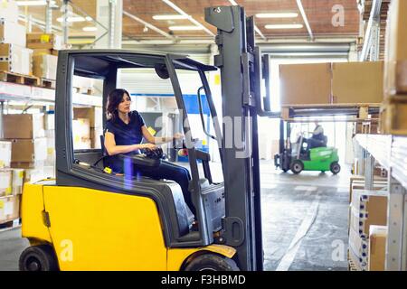 Female forklift truck driver working in distribution warehouse Stock Photo