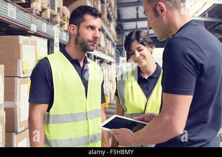 Warehouse workers using digital tablet in distribution warehouse Stock Photo