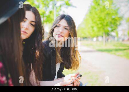 Three young female friends having conversation in park Stock Photo