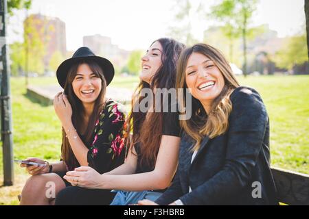 Portrait of three young female friends laughing in park Stock Photo