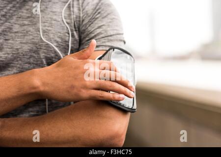 Cropped shot of male runner choosing music on smartphone armband Stock Photo