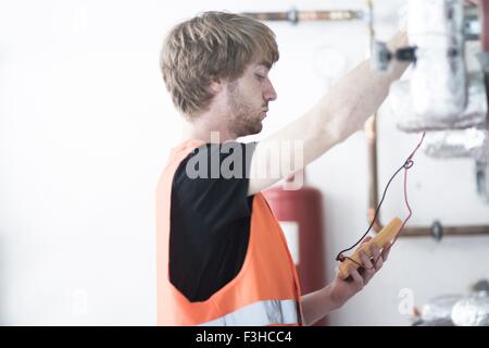 Side view of young man wearing high visability vest testing heating system Stock Photo