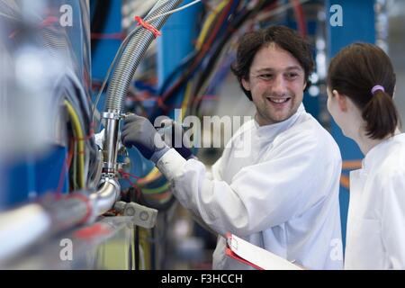 Male and female colleagues wearing lab coats, face to face smiling Stock Photo