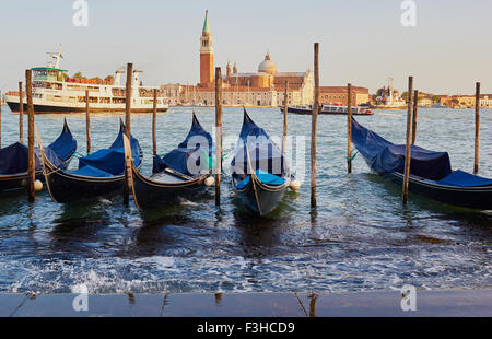 Gondolas moored on Venetian waterfront with San Giorgio Maggiore island and Basilica in background Venice Veneto Italy Europe Stock Photo