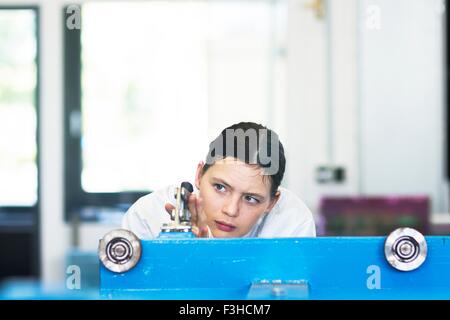 Head and shoulders of young woman operating machine Stock Photo