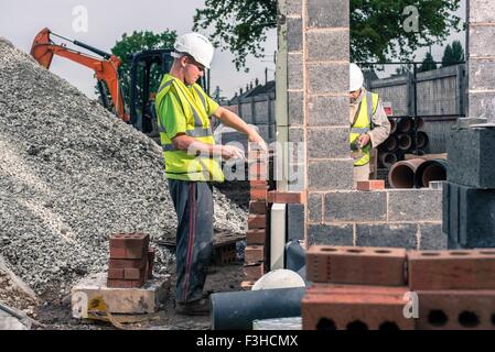 Workers laying bricks on construction site Stock Photo