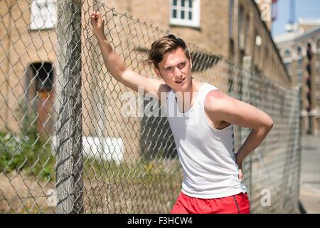 Runner stretching against wire fence, Wapping, London Stock Photo