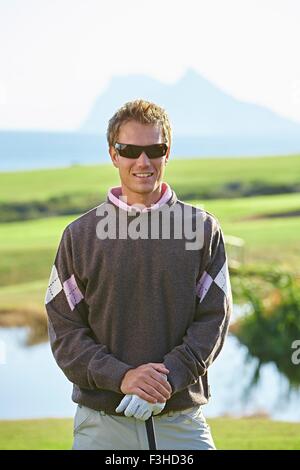 Golfer wearing sunglasses looking at camera smiling