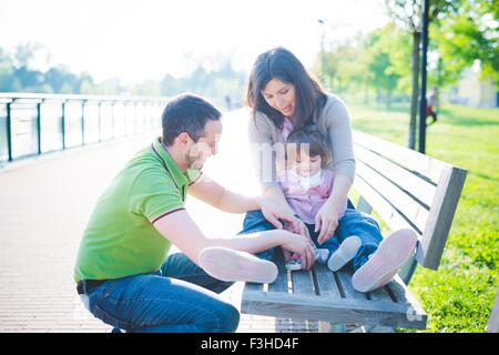 Mid adult couple with toddler daughter on park bench